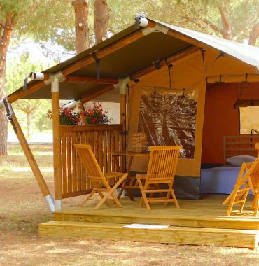 Tenda glamping in legno immersa nella natura, atmosfera accogliente e rilassante.